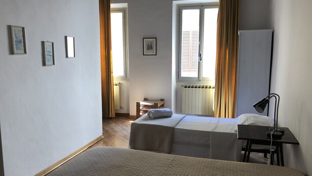 A bedroom with two beds, a desk, a chair, and a radiator. - Macci Number Eight (Florence)