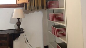 A room with a wooden cabinet, a lamp, and striped storage boxes. - Macci Number Eight (Florence)