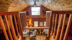 A wooden interior with a high ceiling, a central seating area with a sofa and chairs, and a view through a window. - 🐾Gray Wulff - This rustic dog friendly camp sits on the shore of Quimby Pond (Rangeley)