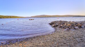 A rocky shoreline with calm water and a wooden dock. - Rangeley Manor 7 | Cozy Cottage with Shared Access to Rangeley Lake (Rangeley)