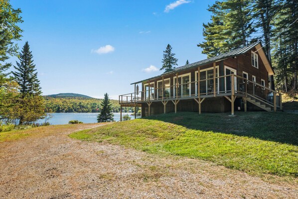 A lodge with a deck overlooking a lake, surrounded by trees.