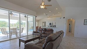 A spacious living area with a leather sofa, a coffee table, and a ceiling fan.