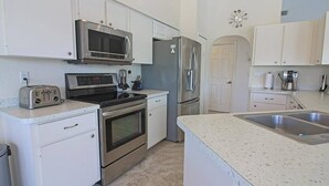 A modern kitchen with stainless steel appliances, white cabinetry, and a granite countertop.