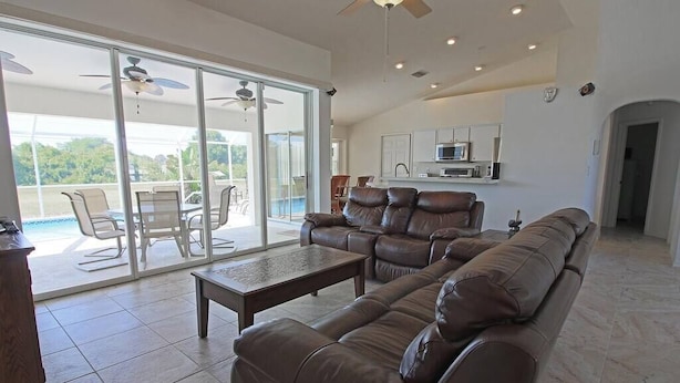 A spacious living room with a leather sofa, a coffee table, and a dining area with chairs.