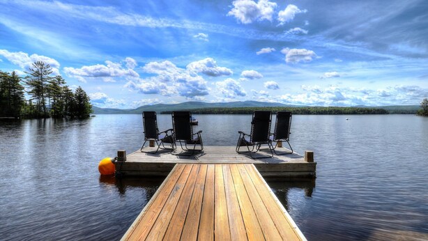 A wooden dock extending into calm water with two rocking chairs and a yellow buoy. - Beach Front Retreat - Private home on Mooselookmeguntic Lake (Oquossoc)