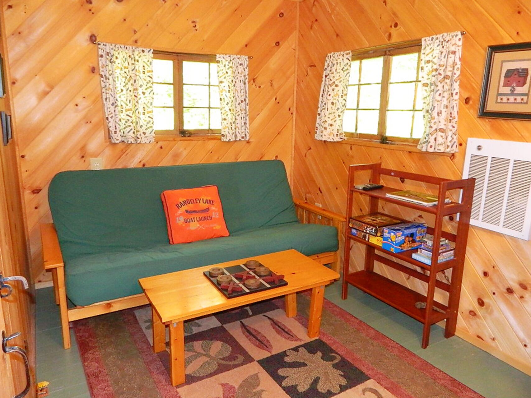 Ein gemütliches Blockhaus-Interieur mit einem grünen Sofa, einem Holztisch und einem Bücherregal.