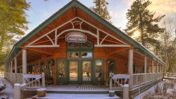 A wooden lodge with a sign reading "Oquosoc Country Suites." - Oquossoc Suite #6 | A/C & Fireplace (Oquossoc)