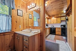 L’intérieur d’un chalet en bois comprend une salle de bain équipée d’un double lavabo, d’un meuble-lavabo et d’un grand miroir.