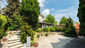 A paved entrance with a 'Welcome' sign, surrounded by potted plants and trees. - Casa Montana II- Country Apartment (Balatonalmadi)