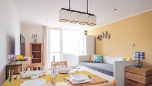 A dining area with a wooden table set for four, a sofa, and a cabinet. - Casa Montana II- Country Apartment (Balatonalmadi)