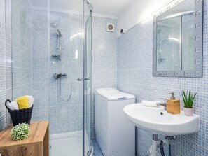 Une salle de bain avec une douche à parois de verre, des toilettes blanches et un lavabo avec un miroir au-dessus.