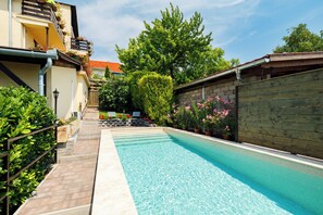 Ein Pool mit Fliesen umgeben von einem Holenzaun und Blumentöpfen.