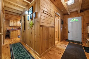 A wooden interior with a dog crossing sign, a door with a window, and a kitchen area with cabinets and a countertop.
