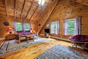 A cozy wooden cabin with a bed, a television, and a chair.