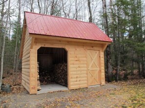 A small wooden shed with a red roof, a door, and an open entrance.