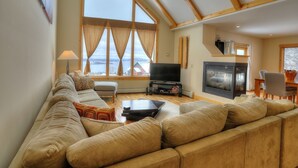 A spacious living room with a large sofa, a television, and a fireplace.