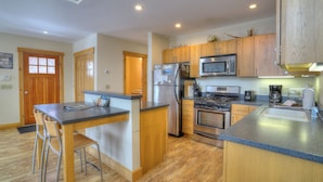 A modern kitchen with wooden cabinets, stainless steel appliances, and a central island with bar stools.