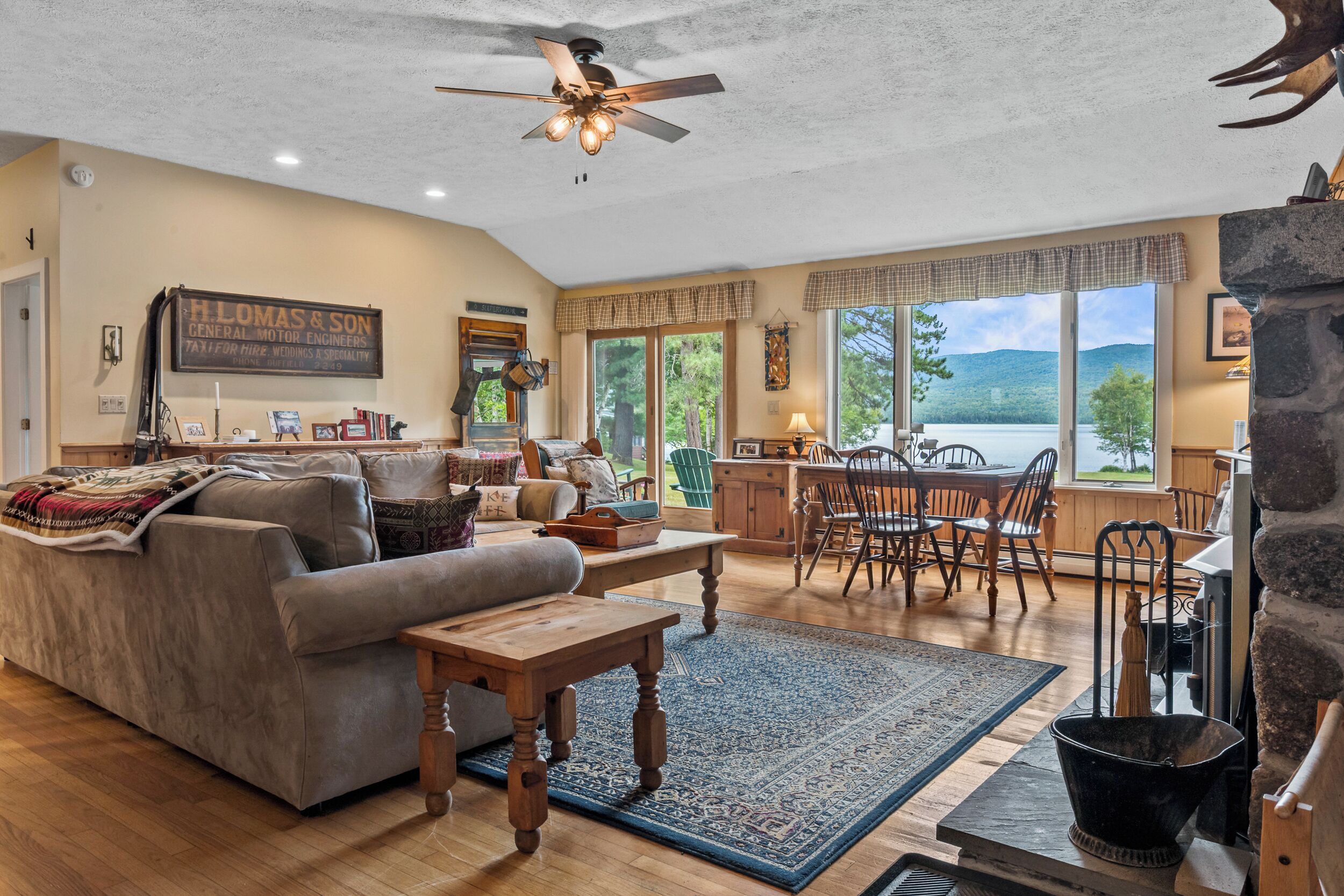 A spacious living room with a fireplace, a dining area, and a large window offering a view of the outdoors.