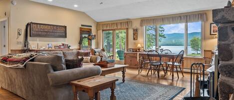 A spacious living room with a fireplace, a dining area, and a large window offering a view of the outdoors.