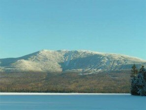 Una muntanya amb un cim cobert de neu i una zona boscosa al primer pla.