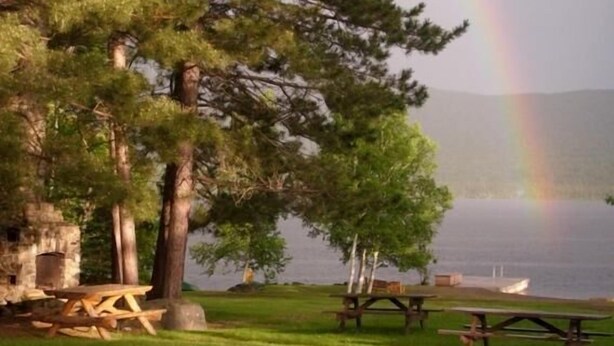 A lakeside picnic area with picnic tables and a stone structure.