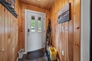 Un interno in legno con una porta bianca, una panca e un cestino giallo.