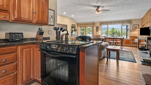 A spacious kitchen with wooden cabinets, a stove, and a dining area with a view.