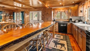 A wooden interior with a kitchen, dining area, and a large window. - Hart | Beautiful family getaway located just three miles from downtown Rangeley (Rangeley)