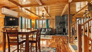 A wooden interior with a dining area, sofa, fireplace, and a staircase. - Hart | Beautiful family getaway located just three miles from downtown Rangeley (Rangeley)
