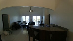 Un espacio abierto que combina sala de estar con una isla de cocina, asientos y vistas al exterior.