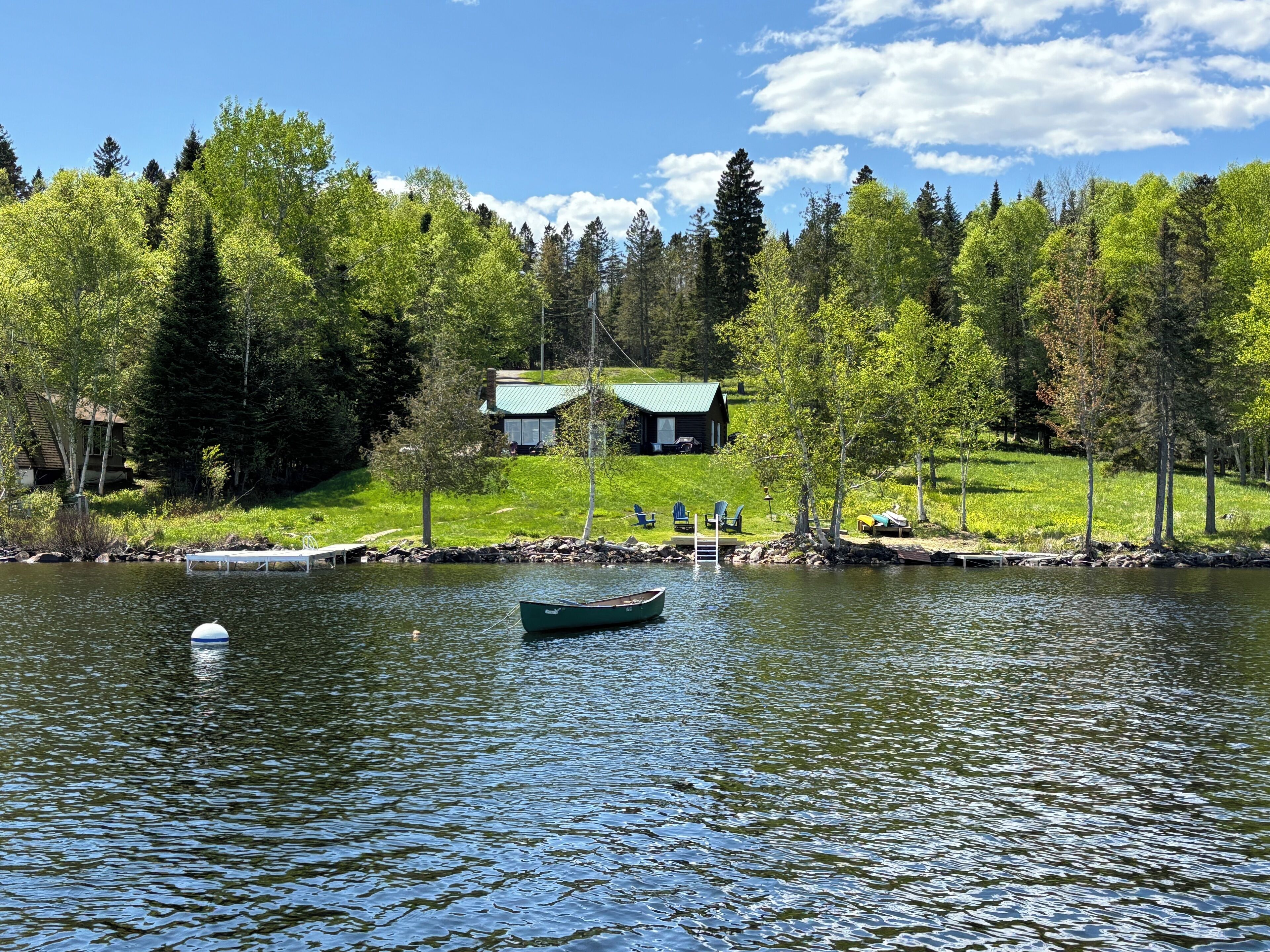 A lakeside cabin with a dock, surrounded by lush greenery and trees.