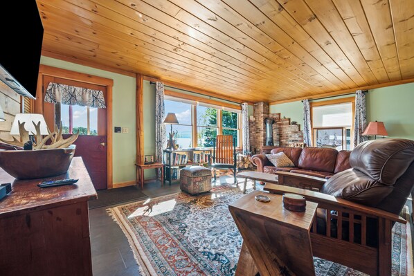 A cozy living room with a wooden ceiling, a leather sofa, a coffee table, and a fireplace.