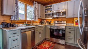 Una cucina con mobili in legno, un forno a microonde, un forno e un frigorifero.