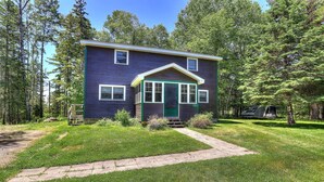 A two-story house with a green door and white-framed windows, surrounded by a grassy yard and trees. - Rangeley Manor P | 4 Bedroom Cabin with Shared Waterfront Access (Rangeley)