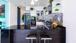 A modern kitchen with a black countertop, stainless steel appliances, and a tiled backsplash. - Villa 29/6 Ocean front pool villa (Tambon Patong)
