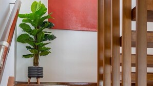 A wooden staircase with a metal handrail, a potted plant, and a red abstract painting on the wall. - Villa 29/6 Ocean front pool villa (Tambon Patong)