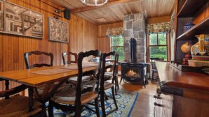 Um interior em madeira com uma mesa de jantar, cadeiras, lareira e estante de livros.