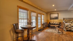 A cozy room with a wooden dining table, two chairs, a sofa, and a rocking chair. - Oquossoc Suite #4 | A/C & Fireplace (Oquossoc)