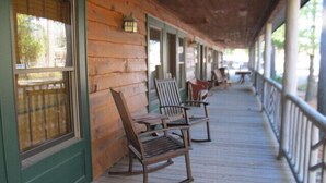 A wooden porch with rocking chairs and a railing. - Oquossoc Suite #4 | A/C & Fireplace (Oquossoc)