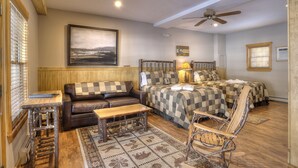 A cozy room with a bed, a wooden bench, a small table, and a chair. - Oquossoc Suite #4 | A/C & Fireplace (Oquossoc)