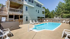 A two-story building with a pool area, including a hot tub, lounge chairs, and a wooden deck. - Jones Beach House | 1200 ft from the beach | Private Pool, Hot Tub | Corolla (Corolla)