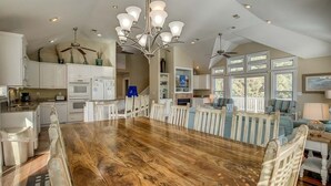 A spacious kitchen with white cabinets, a wooden dining table, and a chandelier. - Jones Beach House | 1200 ft from the beach | Private Pool, Hot Tub | Corolla (Corolla)