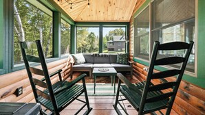 Eine Blockhütte mit Holzbalkendecke, einem Sofa, zwei Sesseln und einem Tisch.