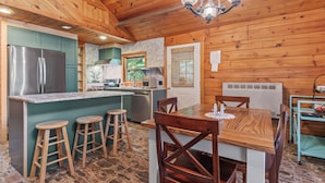 Une cuisine rustique dans un chalet, avec un îlot central, des tabourets en bois et une table à manger avec des chaises.
