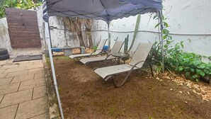Eine Terrassengruppe im Freien mit zwei Lounge-Stühlen und einem Tisch, umgeben von einem Garten mit Kakteen und Pflanzen.
