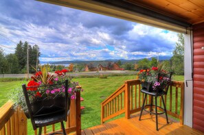 Une terrasse en bois offrant une vue sur un paysage verdoyant et des montagnes.