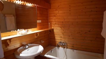 A wooden cabin bathroom with a sink, mirror, and bathtub.