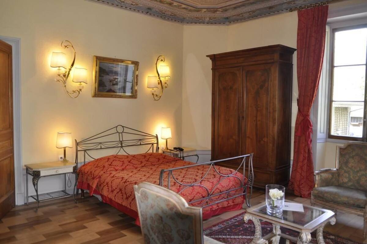 A bedroom with a metal bed frame, a wooden wardrobe, and two wall-mounted lamps.