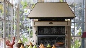 Une cuisine équipée d’un barbecue intégré et d’une variété d’ustensiles de cuisine colorés disposés sur le plan de travail.