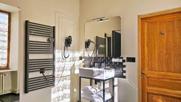 A bathroom with a towel rack, a mirror, a sink, and a door.